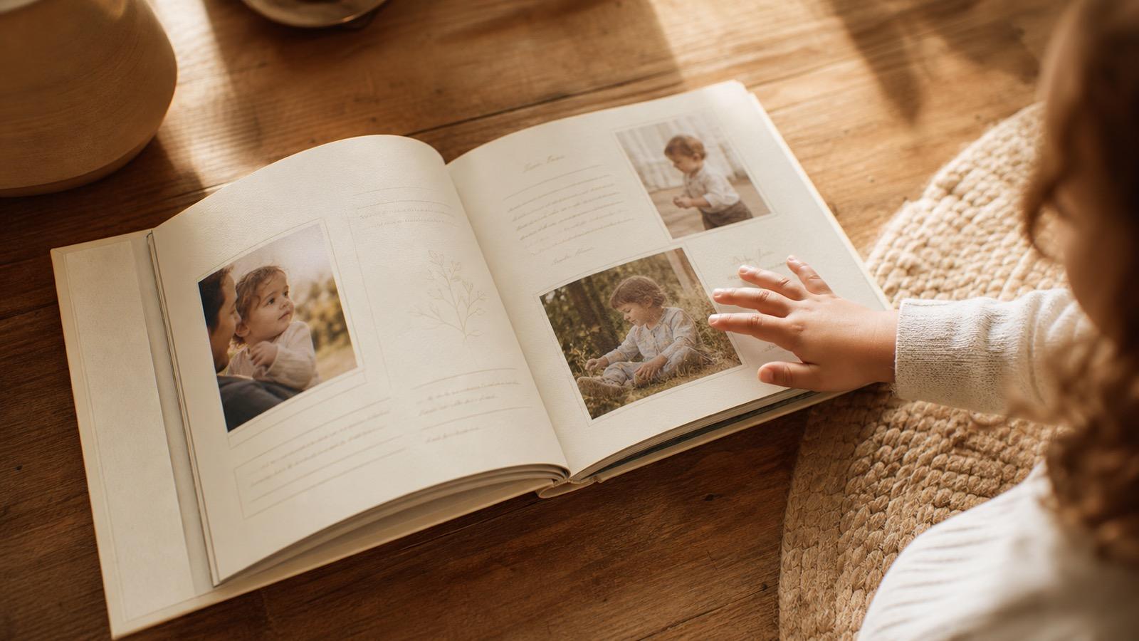A beautifully designed children's memory book on a wooden table with a child's hand reaching toward it
